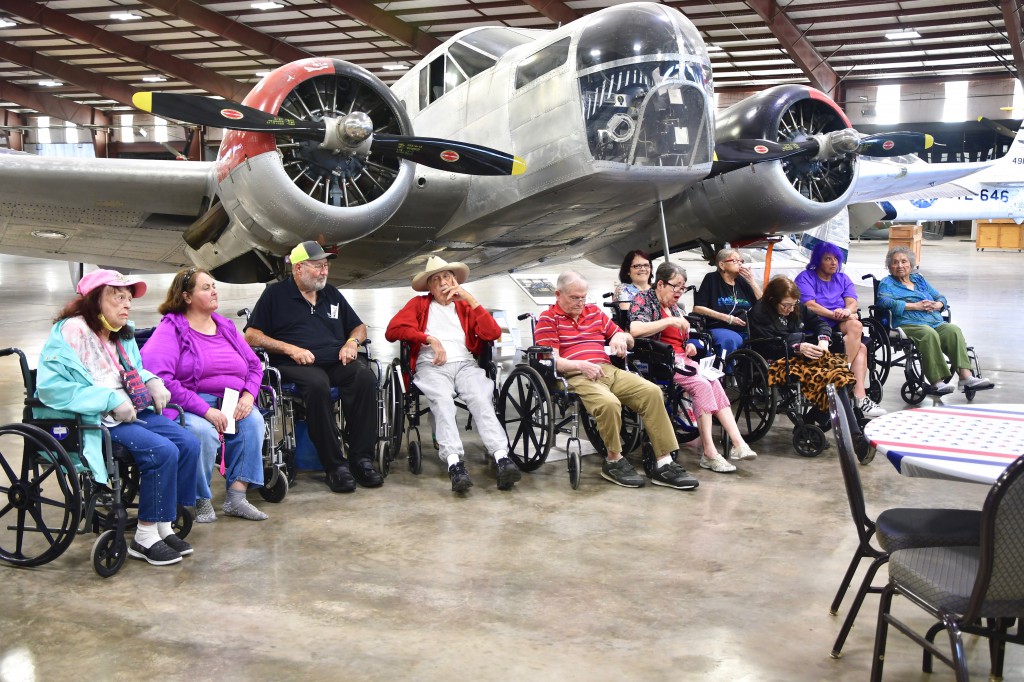 Visitors from Senior Care Midland pose in front of the AT-11 Bombardier Trainer